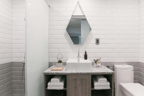 a white bathroom with a sink and a mirror at PAPO'A Hotel in Kaohsiung