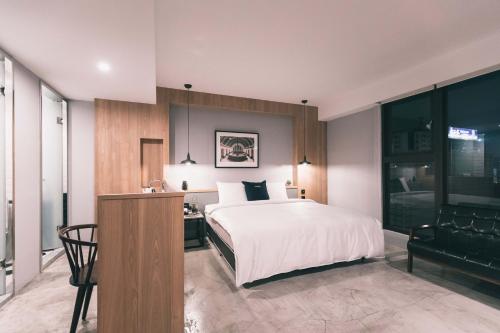 a bedroom with a bed and a desk and a chair at PAPO'A Hotel in Kaohsiung