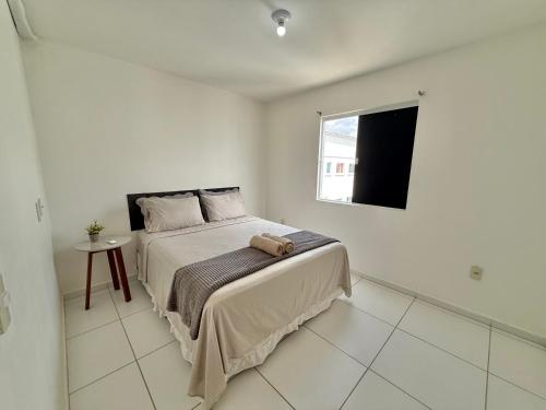 a white bedroom with a bed and a window at Apto Com 2 Ar condicionados, Lava e seca, Wi-Fi in Caruaru