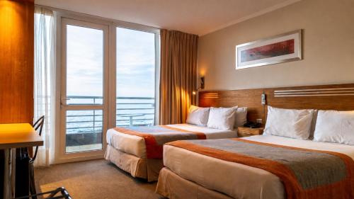 a hotel room with two beds and a large window at Alto del Sol Costanera Antofagasta in Antofagasta