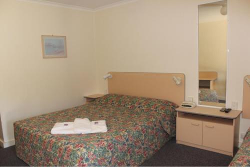 a hotel room with a bed with two towels on it at Mid Coast Motor Inn in Macksville