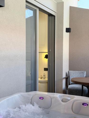 a bath tub in a room with a table at EROS & PATHOS Suites in Kremasti