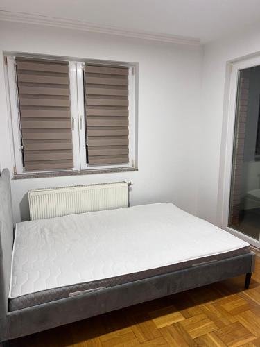 a bed in a white room with a window at Dardi in Peje