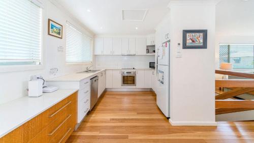 a kitchen with white cabinets and a wooden floor at Lighthouse Unit 1 - Lifestyle Yamba in Yamba