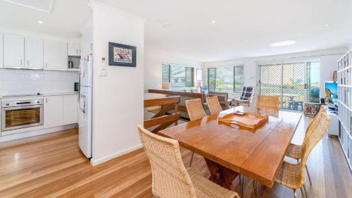 a kitchen and dining room with a wooden table and chairs at Lighthouse Unit 1 - Lifestyle Yamba in Yamba