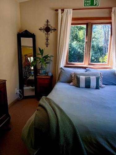 a bedroom with a bed with a window and a mirror at Quaint Country Cottage in Pokororo