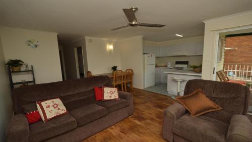 a living room with two couches and a kitchen at Pilot Unit 2 - Lifestyle Yamba in Yamba