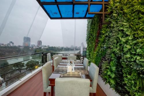 a restaurant with a green wall with a table and chairs at Splendid Hotel & Spa in Hanoi