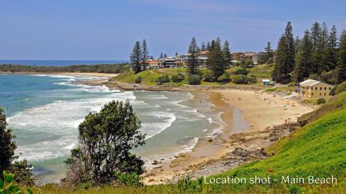 a beach with people on it next to the ocean at Sunnyvale 2 - Lifestyle Yamba in Yamba