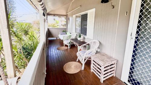 a porch with white chairs and a table on it at Surf Side - Lifestyle Yamba in Yamba