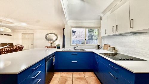 a kitchen with blue cabinets and a white counter top at Yamba Beach House - Lifestyle Yamba in Yamba