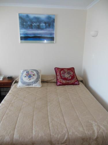a bedroom with a bed with two pillows on it at ASURE Camelot Arms Motor Lodge in Auckland