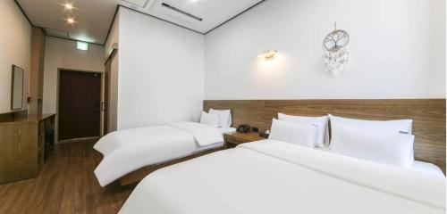 two white beds in a room with a clock on the wall at 호텔 누리다 Hotel Nurida in Sayang-ni