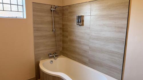 a bath tub in a bathroom with wooden walls at KJ Apartments in Lilongwe