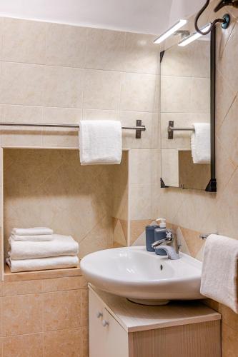 a bathroom with a sink and a mirror and towels at Vitti Stone House - Centro Storico Castellana in Castellana Grotte