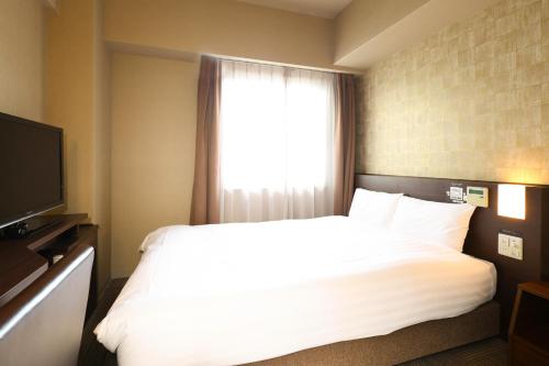 a bedroom with a white bed and a window at Dormy Inn Premium Namba Natural Hot Spring in Osaka