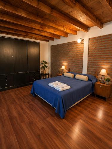 a bedroom with a blue bed and a brick wall at El Refugio de la Trochita in Esquel
