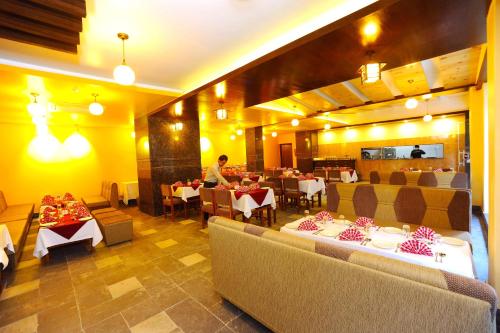 a restaurant with couches and tables and a person in the background at Hotel Queens Park in Pokhara