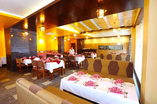 a restaurant with tables and chairs and a chef in the background at Hotel Queens Park in Pokhara