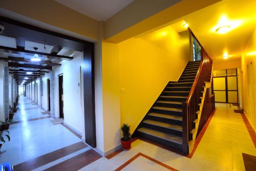 a hallway with stairs and a yellow wall at Hotel Queens Park in Pokhara