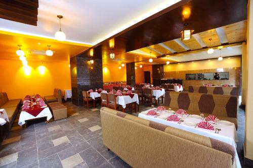 a dining room with tables and chairs and tablesearcher at Hotel Queens Park in Pokhara