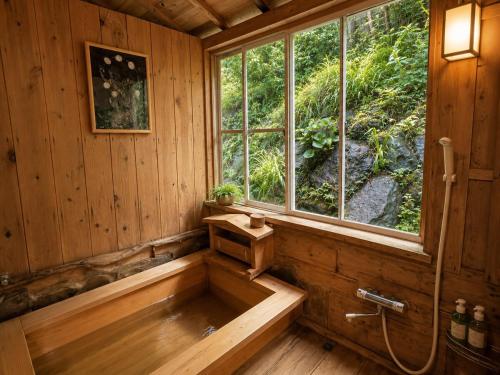 a bath tub in a wooden room with a window at Villa Knossos in Higashiizu