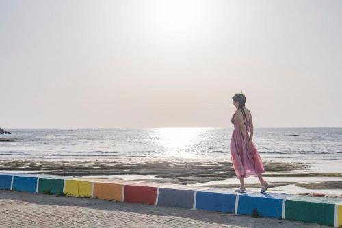 a woman walking on the beach near the water at Vinolian Ocean View Spa Pension in Goseong