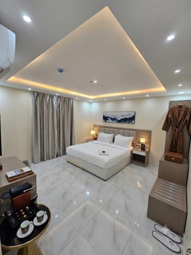 a large bedroom with a white bed and a table at فندق الضيافة in Abu Arish