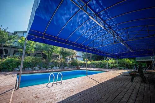 a large blue umbrella over a swimming pool at Gapyeong Solgogae Pension in Gapyeong