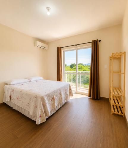 a bedroom with a bed and a large window at Sobrado do Papagaio in Palhoça