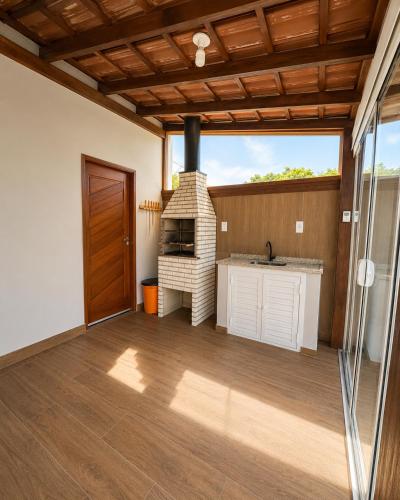 a living room with a fireplace and a kitchen at Sobrado do Papagaio in Palhoça