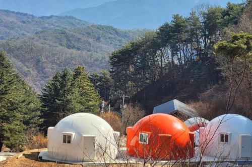 three white and orange domes in front of a mountain at Wonju Forest Dome in Wonju