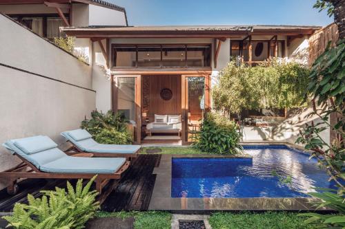 a backyard with a swimming pool and a house at Teratai Villa Canggu by Ini Vie Hospitality in Canggu