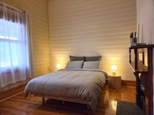 a bedroom with a bed with two lamps and a window at Cosy Cottage in Port Broughton