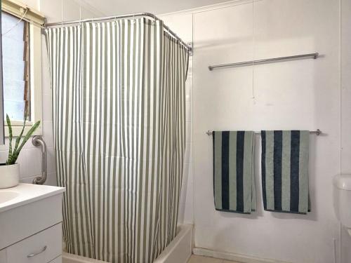 a bathroom with a shower with a striped shower curtain at Cosy Cottage in Port Broughton