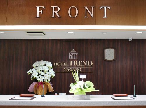 a room with a hotel sign and flowers on a table at Hotel Trend Nagano in Nagano