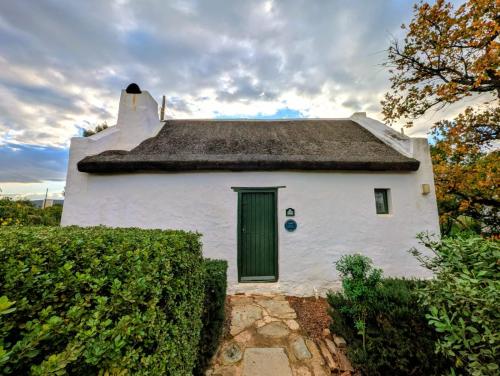 a house with a thatched roof with a green door at Old Corner Cottage in McGregor