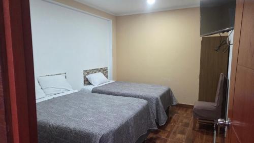 a hotel room with two beds and a chair at La casona de aquiles in Palle Nuevo