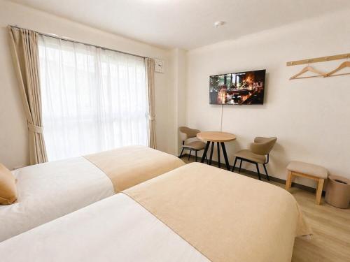 a hotel room with two beds and a table and a window at 海しずく Slow in Amakusa