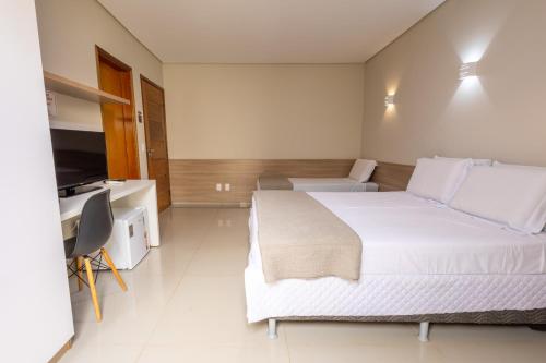 a hotel room with a large bed and a television at Rosa Vilma Hotel in Chapadão do Sul