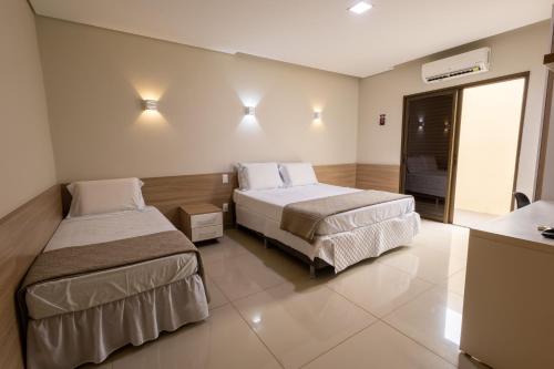 a hotel room with two beds and a television at Rosa Vilma Hotel in Chapadão do Sul