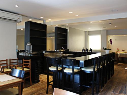 a kitchen with a bar with chairs and a sink at SW Praia Hotel in Praia Grande