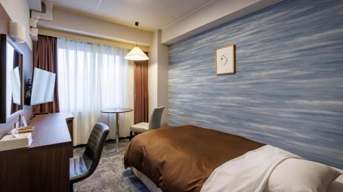 a hotel room with a bed and a desk at Hotel Excel Okayama in Okayama