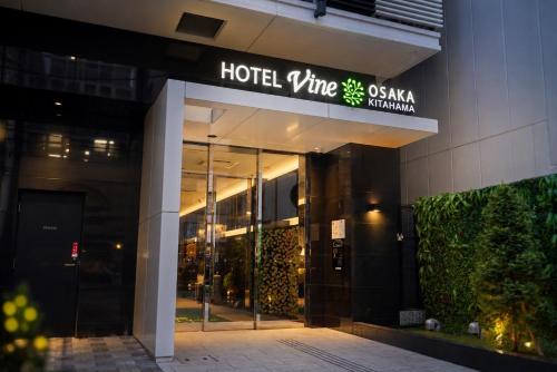 a hotel entrance with a sign on a building at HOTEL VINE OSAKA KITAHAMA in Osaka
