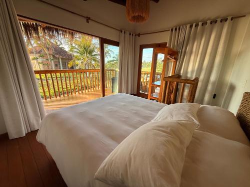 a bedroom with a bed and a large window at Corumbau Bangalôs in Corumbau
