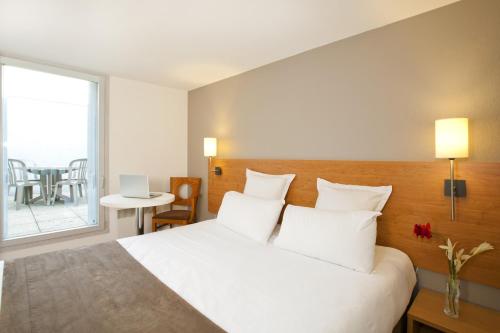 a bedroom with a bed with white pillows and a window at Séjours & Affaires Nantes Ducs De Bretagne in Nantes