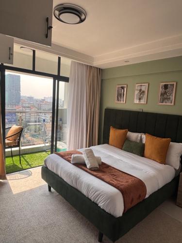 a bedroom with a large bed with a large window at Serenity Spot - Cozy 1 bedroom with AC and Heater with City View in Nairobi, Westlands in Nairobi