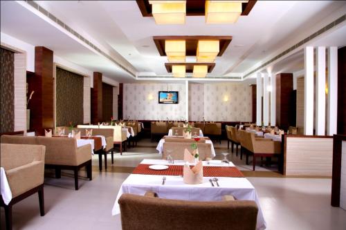 uma sala de jantar com mesas, cadeiras e luzes em Hotel Excalibur em Kottayam