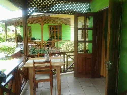 eine Veranda mit einem Tisch und Stühlen sowie ein grünes Haus in der Unterkunft Villa Creole in La Digue