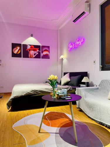 a living room with a bed and a table with flowers at Bee's House in Hanoi